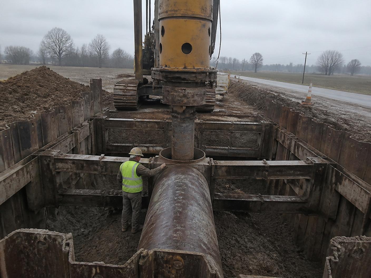 Auger boring machine set in a shored excavation pit on a rural road crossing